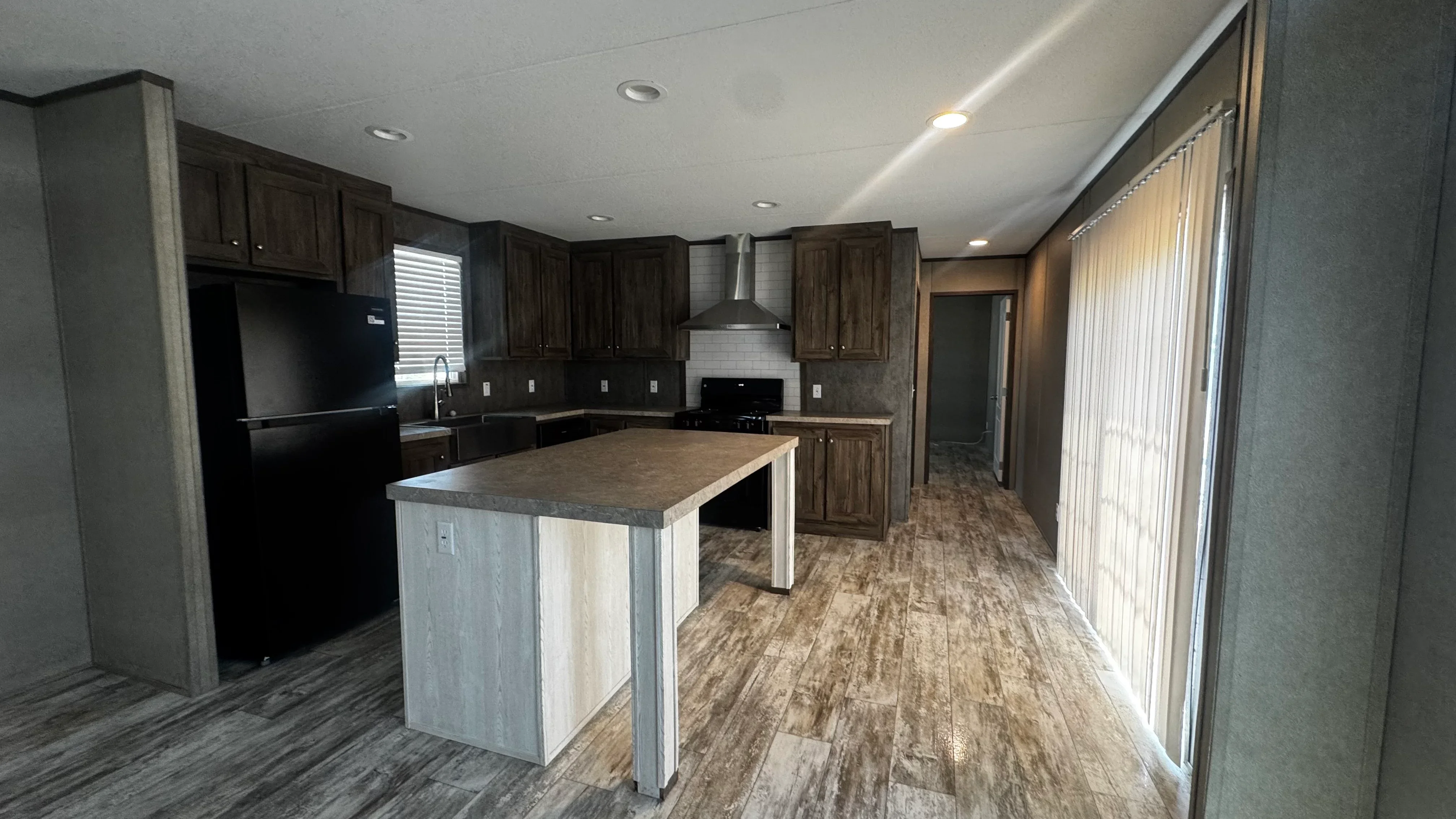 Kitchen with dark wood cabinets, white tile backsplash, gray quartz island, and vinyl plank flooring
