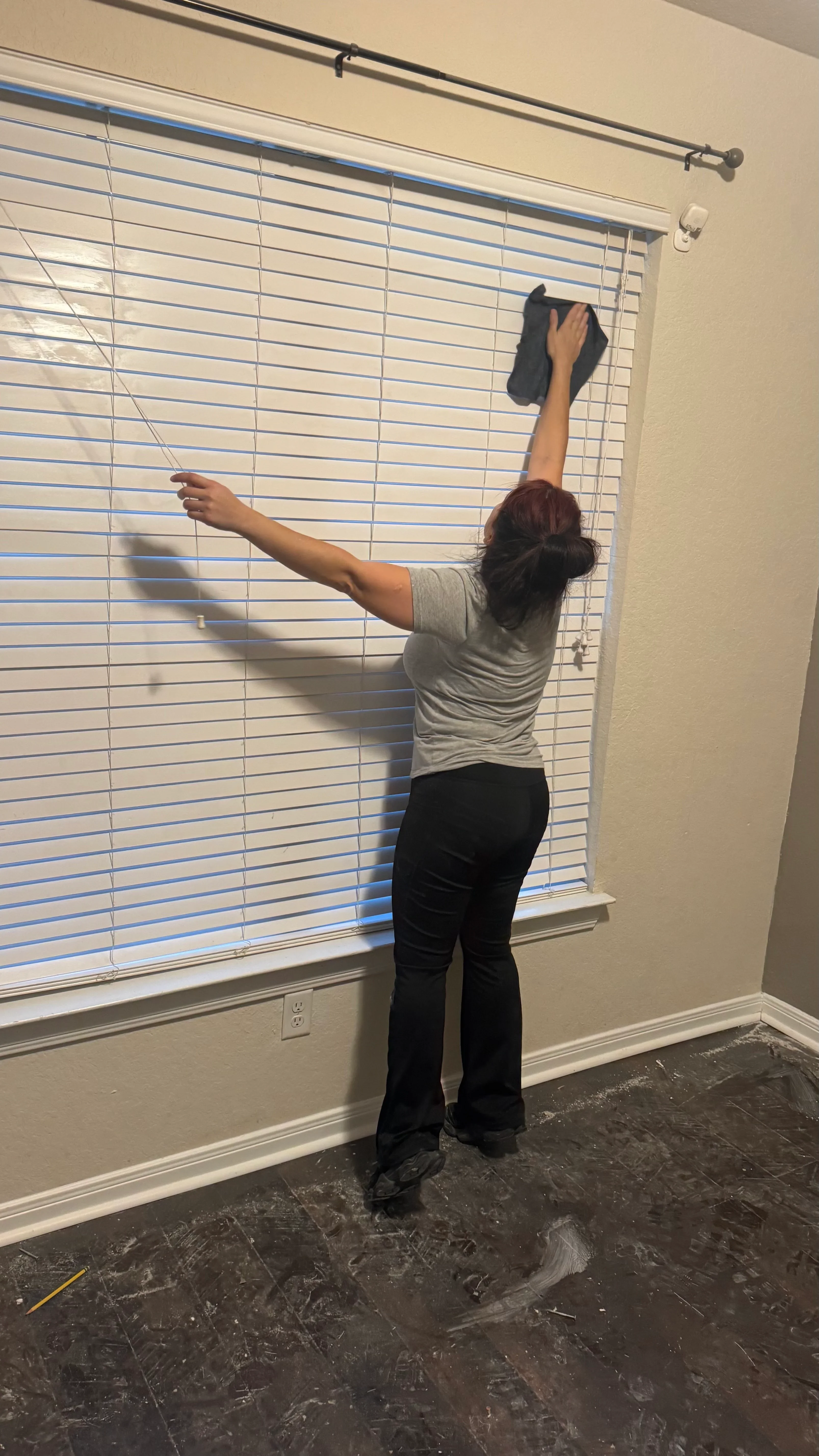 Worker cleaning horizontal aluminum blinds with microfiber cloth, detailed slat-by-slat cleaning