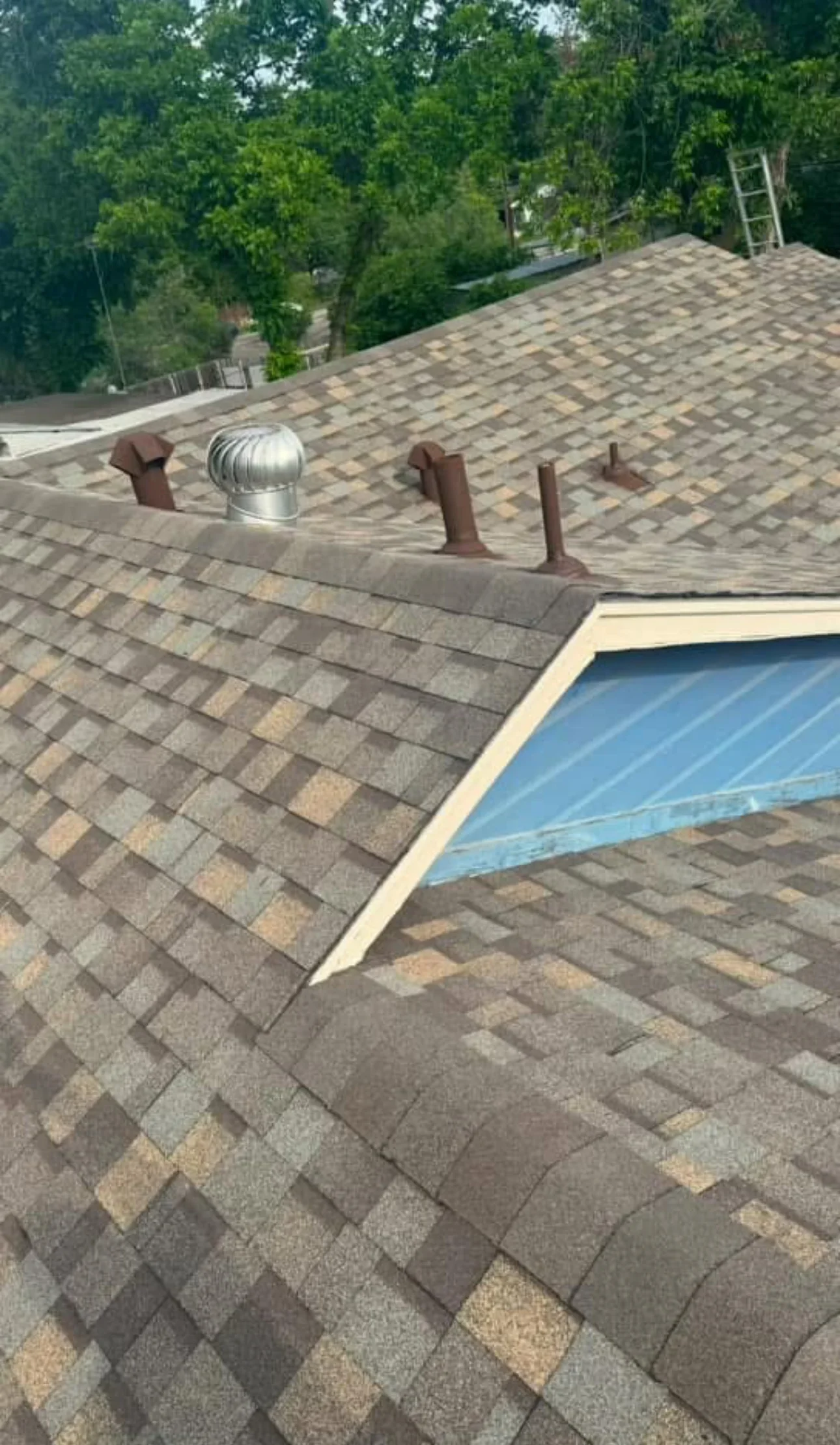 New architectural shingle roof with gray and tan blend, ridge vents, and metal flashing