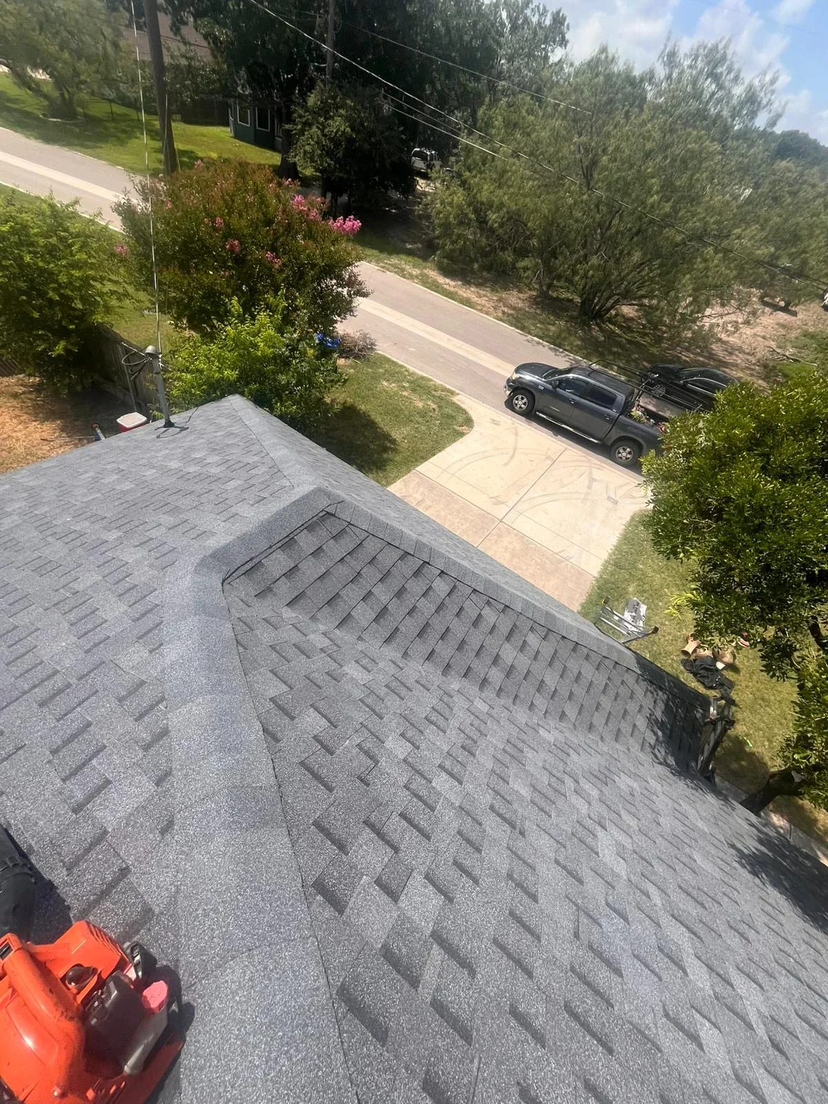 Charcoal gray dimensional asphalt shingles installed on residential roof with proper ridge cap detail