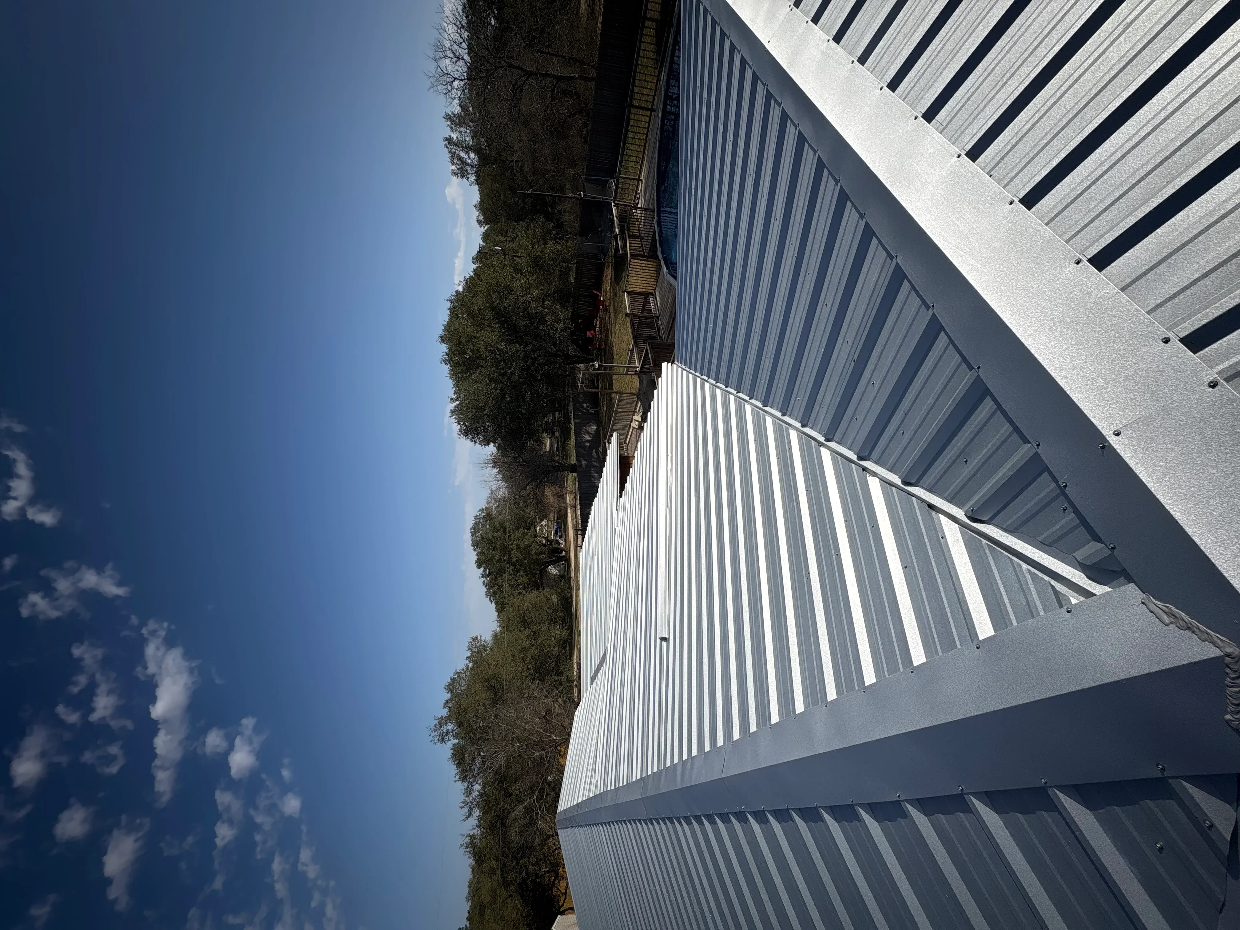 White corrugated metal roof panels with standing seams installed on residential structure