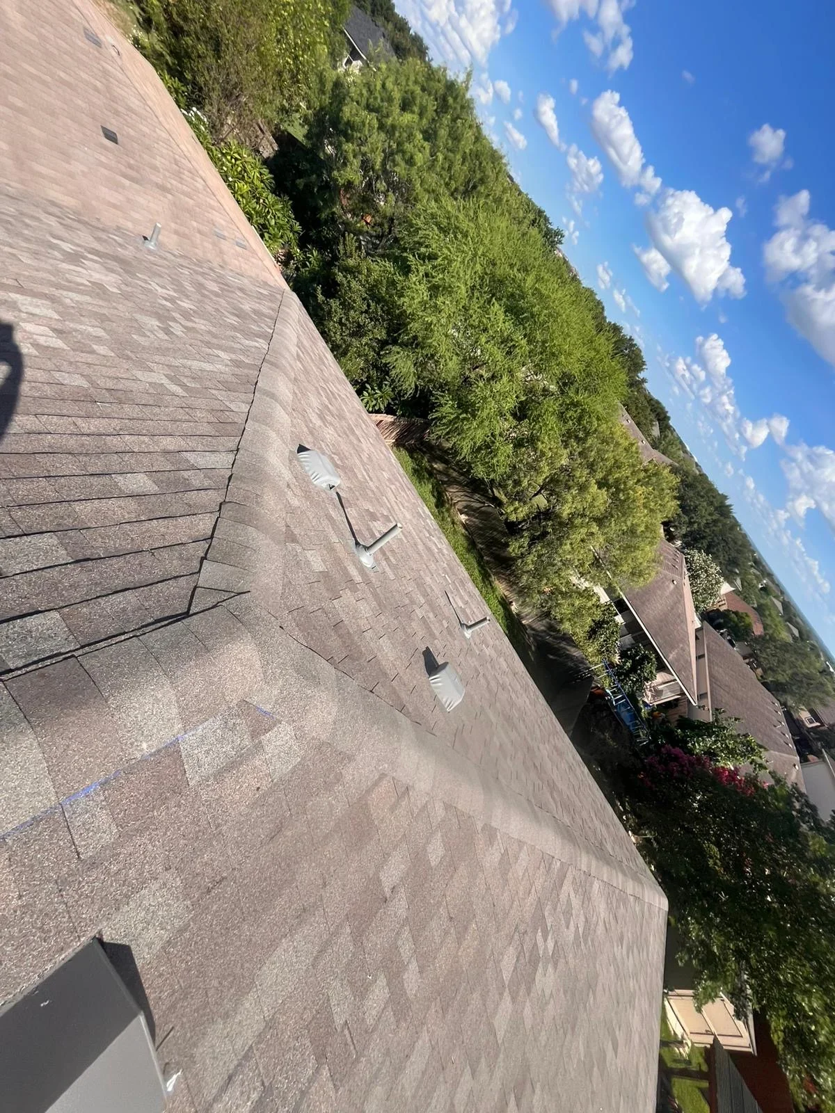 Newly installed asphalt shingle roof with gray composition shingles and roof vents on residential home