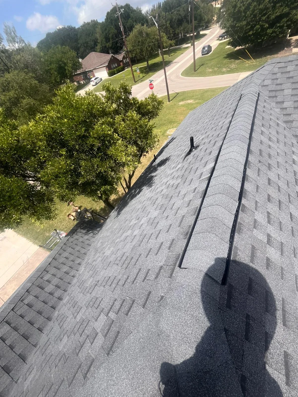 Gray architectural shingles with ridge vent and black flashing on residential roof