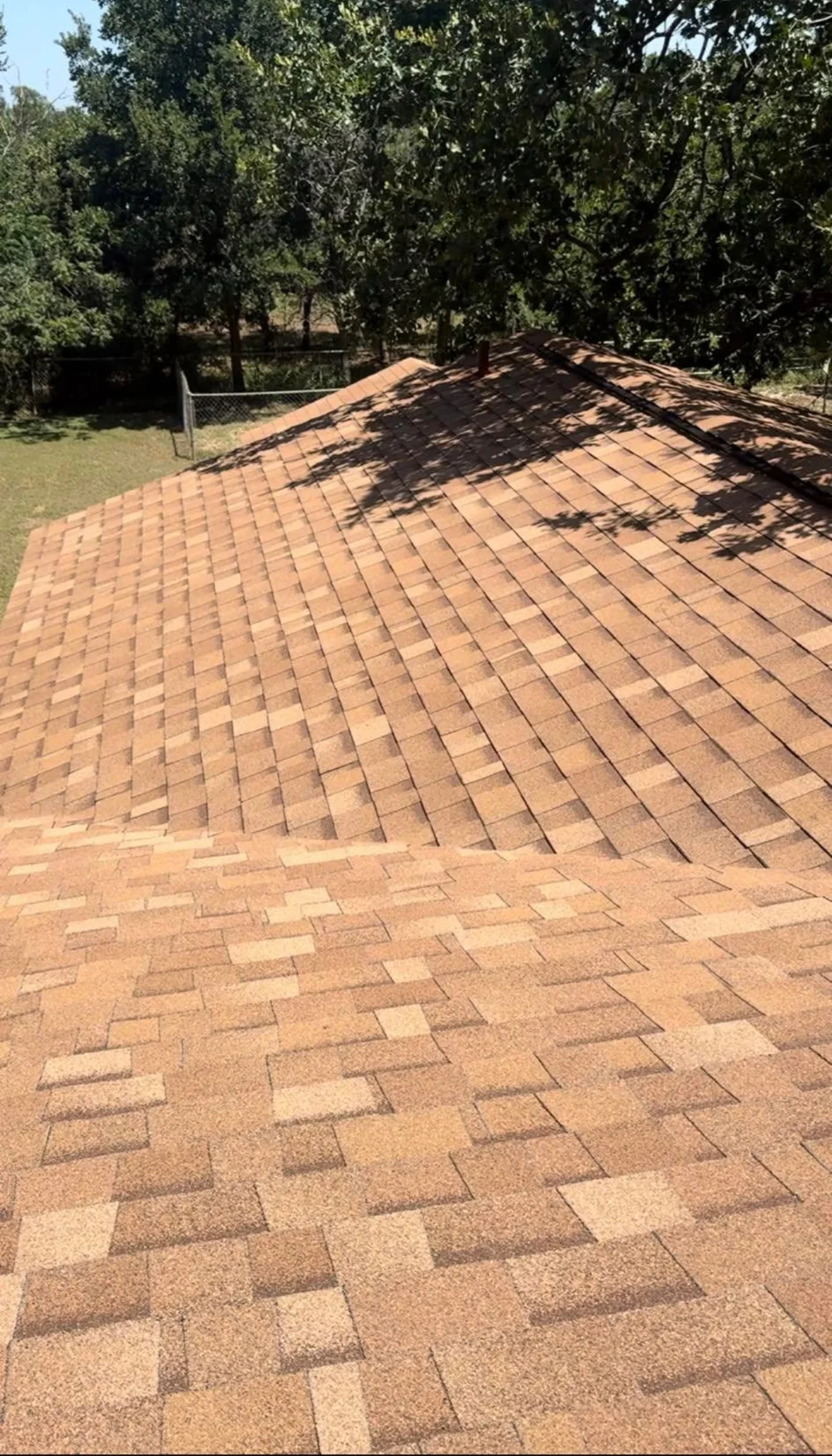 Newly installed architectural shingles in terracotta, staggered pattern on pitched roof