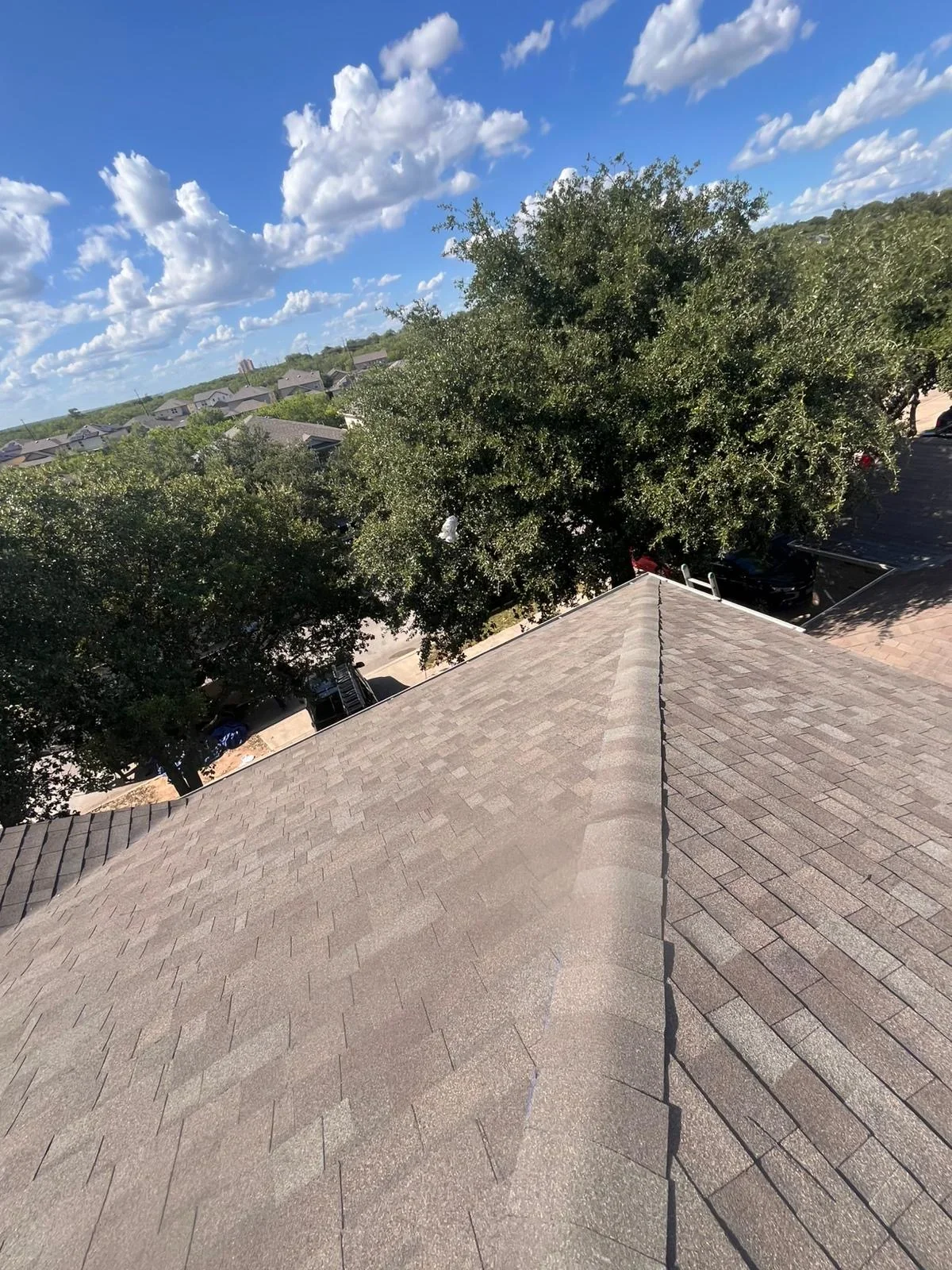 Newly installed gray architectural shingles on residential roof with metal trim and ridge cap