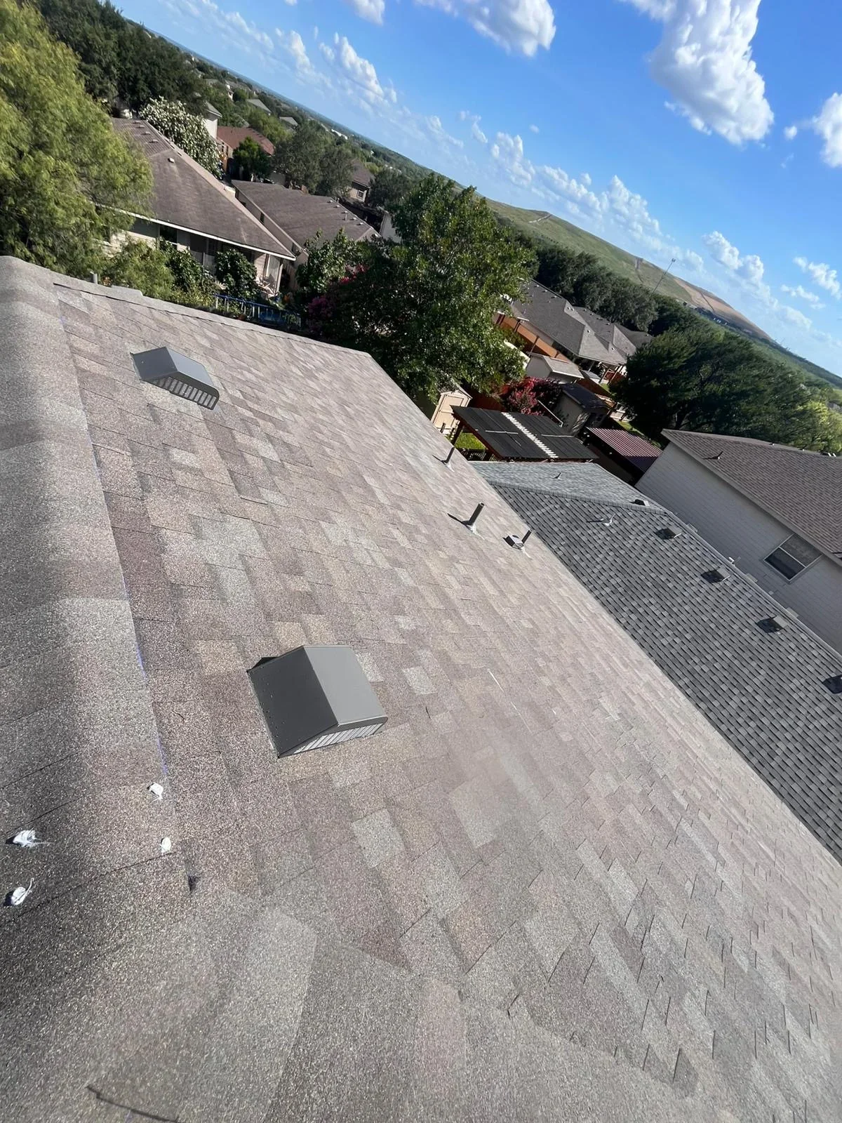Gray asphalt shingle roof with roof vents and ridge caps on residential home