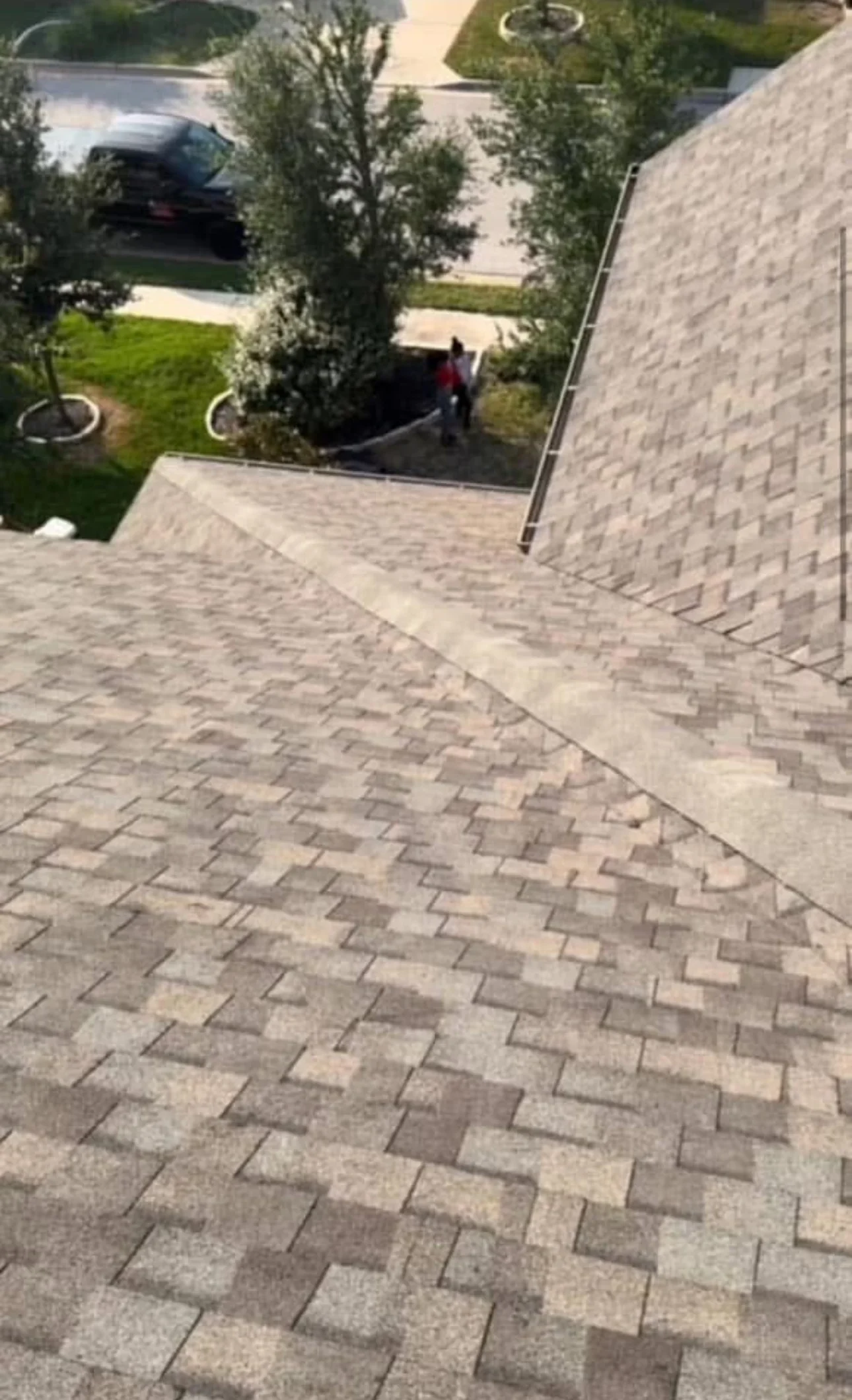 Aerial view of newly installed gray architectural shingles with herringbone pattern and metal flashing trim