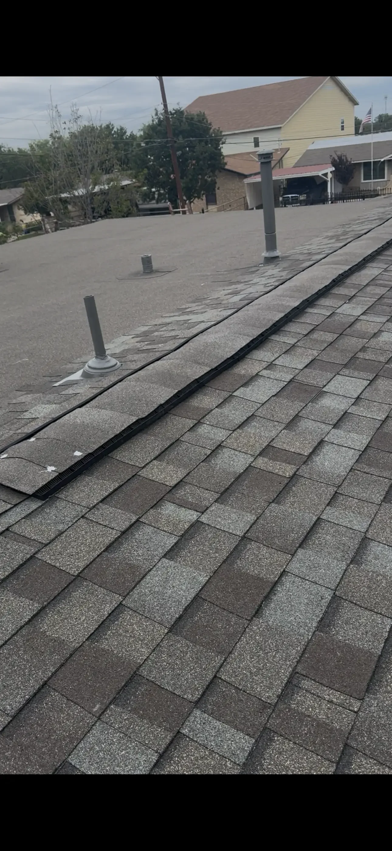 Newly installed asphalt shingle roof with gray and charcoal shingles, flashing, and drip edge