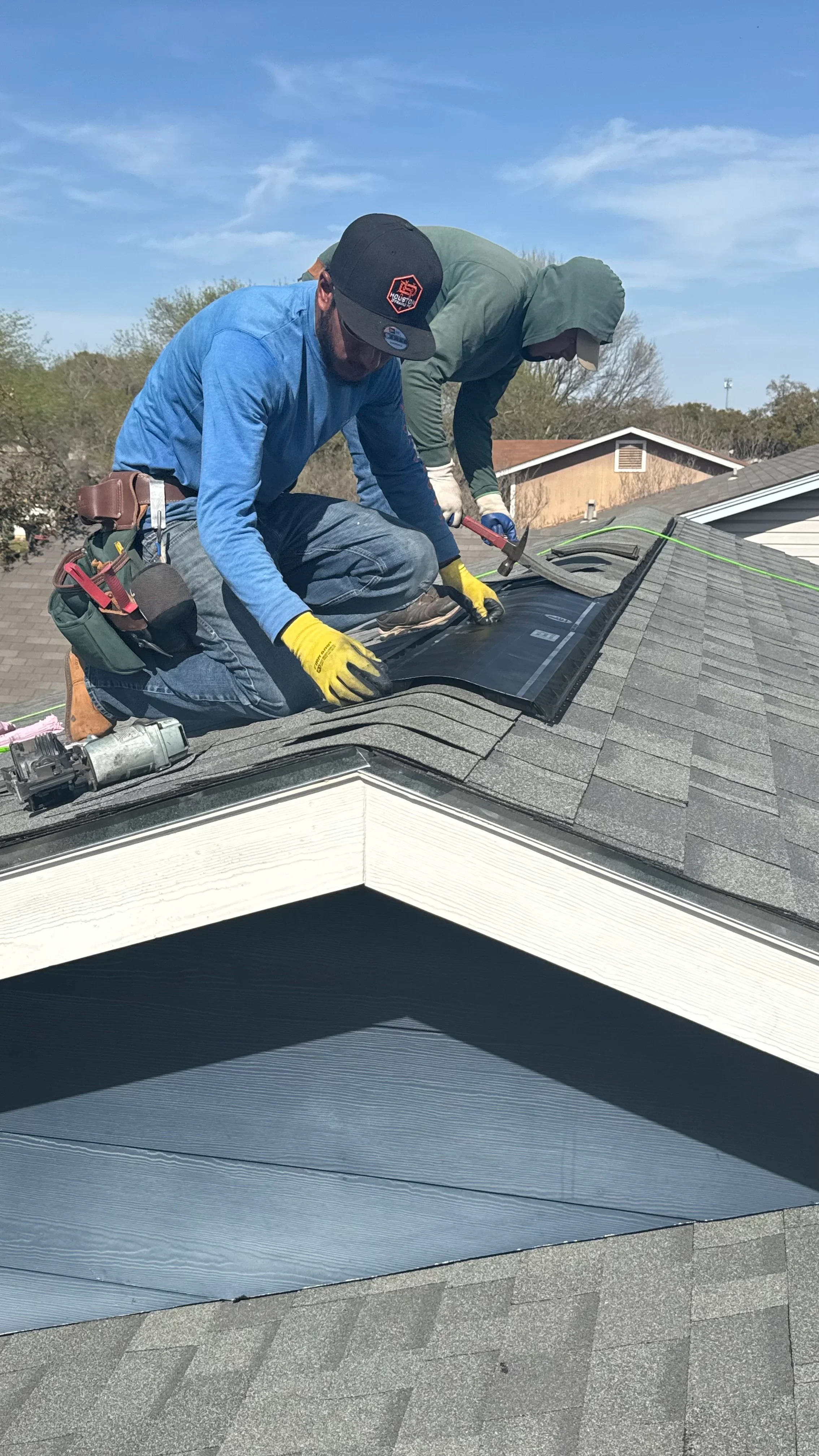 Roofer installing black EPDM membrane and metal flashing on residential roof valley